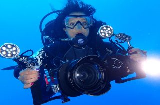 Ayisha holding an underwater camera and SCUBA diving in the ocean