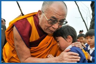 Dalai Lama and a child who appears to be sad, embracing