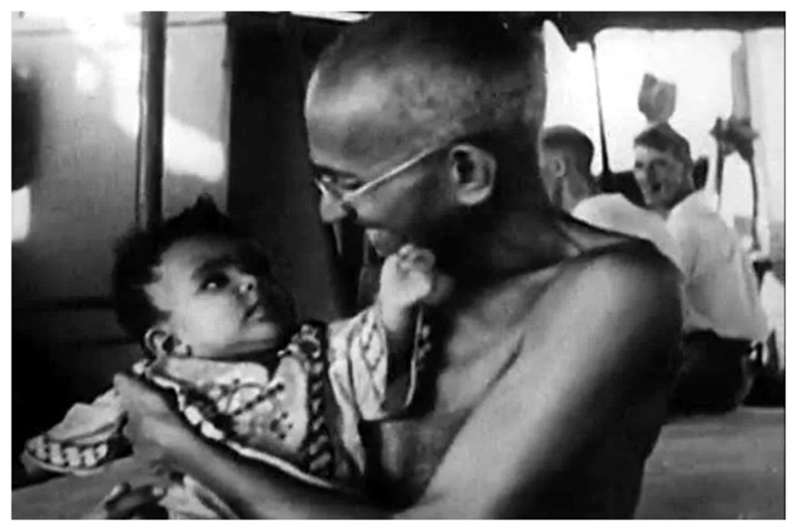 A baby and a smiling Mahatma Gandhi looking at each other