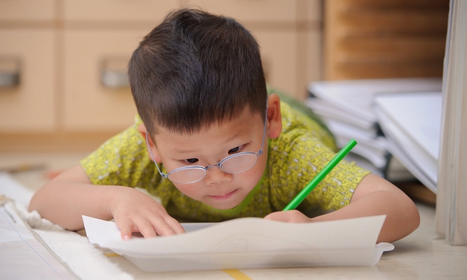 Young boy absorbed in writing.